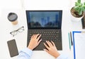 Top view of businesswoman`s hands typing on a laptop on modern white office desk table Royalty Free Stock Photo