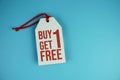 Buy one get one free text on tag sale flat lay on blue background Royalty Free Stock Photo