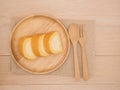 Top view cake roll in wooden dish with wooden spoon and fork on beige wooden table,background