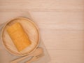 Top view cake roll in wooden dish with wooden spoon and fork on beige wooden table,background