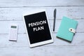 Top view of calculator,notebook,pen and tablet pc written with 'PENSION PLAN' on wooden background Royalty Free Stock Photo