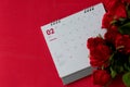 Top view calendar of February with blurred red rose flower on the red background desk the concept for Valentine\'s day