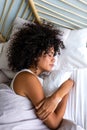 Top view of calm and serene young multiracial woman with curly hair sleeping in bed at home cozy bedroom. Vertical
