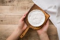 Top view on Camembert cheese on wooden board in woman`s hands. Serving French homemade soft cheese. Food concept