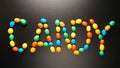 TOP VIEW: Candy letters by colorful candies on black background Royalty Free Stock Photo