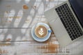 Top view of cappuccino with latte art coffee cup and laptop computer on wooden background Royalty Free Stock Photo