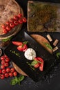 Top view Caprese salad. Mozzarella cheese, tomatoes and basil herb leaves on black plate over wood cuts, stone table in Royalty Free Stock Photo