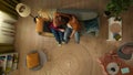 Top view capturing a young couple sitting on the couch together. The woman seems frustrated and her partner tries to