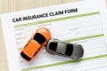 Top view of car insurance claim form with car toy crash on wooden desk. Royalty Free Stock Photo