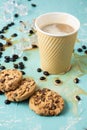 Top view of a cardboard cup with cappuccino coffee on a blue table, spilled coffee, coffee beans