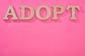 Top view of cardboard word adopt on pink background with copy space.