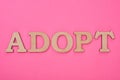 Top view of cardboard word adopt on pink background.