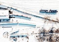 Top view of cargo trains and locomotive depot. Aerial view from flying drone of snow covered freight trains on the railway station