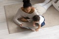 Caring African American mother reading book to toddler daughter