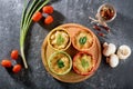 Top view of casserole with baked cheese, chicken and mushrooms in cocoanuts with vegetables on gray background