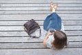 Top view casual wearing woman with trendy leather bag sitting on wooden bench in the park and drinking hot coffee on-the-go.