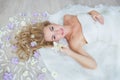 TOP VIEW: Caucasian blonde bride lies on a floor with a field flowers