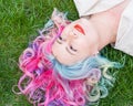Top view of Caucasian woman with multi-colored hair lying on green grass. Royalty Free Stock Photo