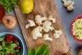 top view of cauliflower pieces with spinach lemon on cutting board with cabbage slices coriander salt and vegetable salad on blue