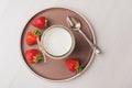 Top view on ceramic plate with homemade Greek yogurt in a glass jar and strawberry on wooden table. Calcium dairy fresh product