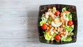 Top view of Cesar salad with prawns in black bowl