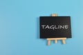 Top view of chalkboard written with TAGLINE isolated on blue background