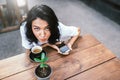 Top view of charming Caucasian female with pleasant cheerful smile sitting at terrace cafe, drinking coffee and enjoying online Royalty Free Stock Photo