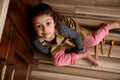 Top view charming little child girl sitting barefoot on floor with scattered wooden spoons looking dreamily up at camera Royalty Free Stock Photo