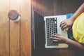 Top view of charming young hipster girl hands working on her laptop sitting at wooden table in a coffee shop. Royalty Free Stock Photo