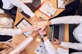 Top view of cheerful business team keeping hands together as a symbol of unity while working together in the modern office