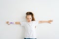 Top view of cheerful cute little girl with broken hand wrapped in plaster bandage with colorful draw lying on white Royalty Free Stock Photo