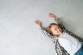 Top view of cheerful pretty child girl lying on white floor with hands up, looking at camera. Royalty Free Stock Photo
