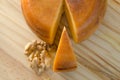 Top view of cheese wheel and slice with nuts over a wooden table Royalty Free Stock Photo