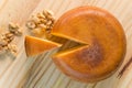 Top view of cheese wheel and slice with nuts over a wooden table Royalty Free Stock Photo