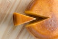 Top view of cheese wheel and slice over a wooden table