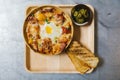 Top view of Cheesy Breakfast Potatoes with Crispy Bacon and Fried egg. Served with Toasts and Prickled Chili