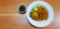 Top view of Chicken Biryani with yellow rice, fried onion, sliced cucumber on white dish or plate with sweet sauce on wooden table Royalty Free Stock Photo