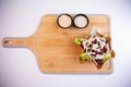 Top view of a chicken tostada salad bowl and cream sauces on a wooden cutting board