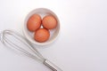 Top view of chickken eggs in a bowl and egg whisks on white background. Royalty Free Stock Photo