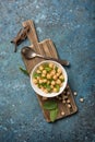 Salad with cooked or canned chickpeas and fresh mint in white bowl on rustic wooden board