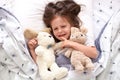 Top view of child crying in bed, sad kid on pillow in bedroom, liitle girl lying on linens with dandelion, upset toddler in pajama Royalty Free Stock Photo