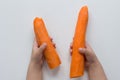 Top view of child hands holding two peeled carrots on the white background Royalty Free Stock Photo