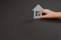 Top view on child hands holding white paper house on gray background . Family home and real estate concept. Royalty Free Stock Photo