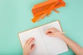 Top view of child hands writing in an empty notebook. Doing homework concept. Orange color. Royalty Free Stock Photo