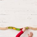 Top view on child`s hand playing with toy train and railway on white wooden table background Royalty Free Stock Photo