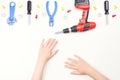 Top view on child`s hands with colorful toys tools on the white background.