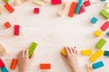 Top view on child`s hands playing with colorful wooden bricks on white table background. Boy building with wooden constructor. Royalty Free Stock Photo