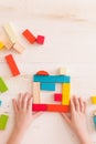 Top view on child`s hands playing with colorful wooden bricks on the white table background.Kid building Royalty Free Stock Photo