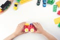 Top view on child`s hands playing with toy train and many toys on the white table background. Royalty Free Stock Photo