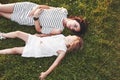 Top view of children and mother laying down on the grass filled with sunshine and looking at each other